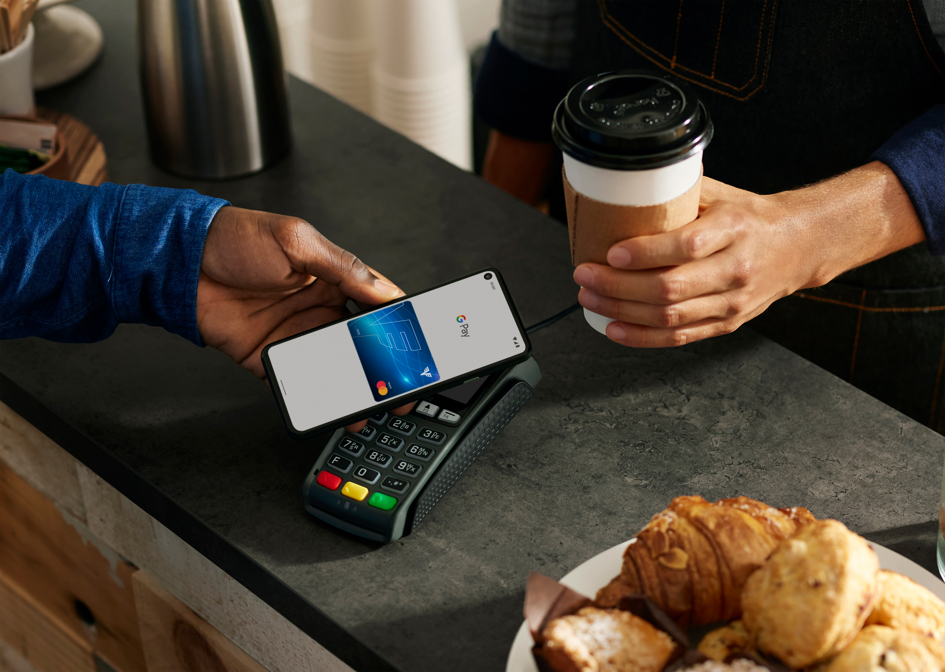 Ein Mann zahlt mit Google Pay am Smartphone im Café.