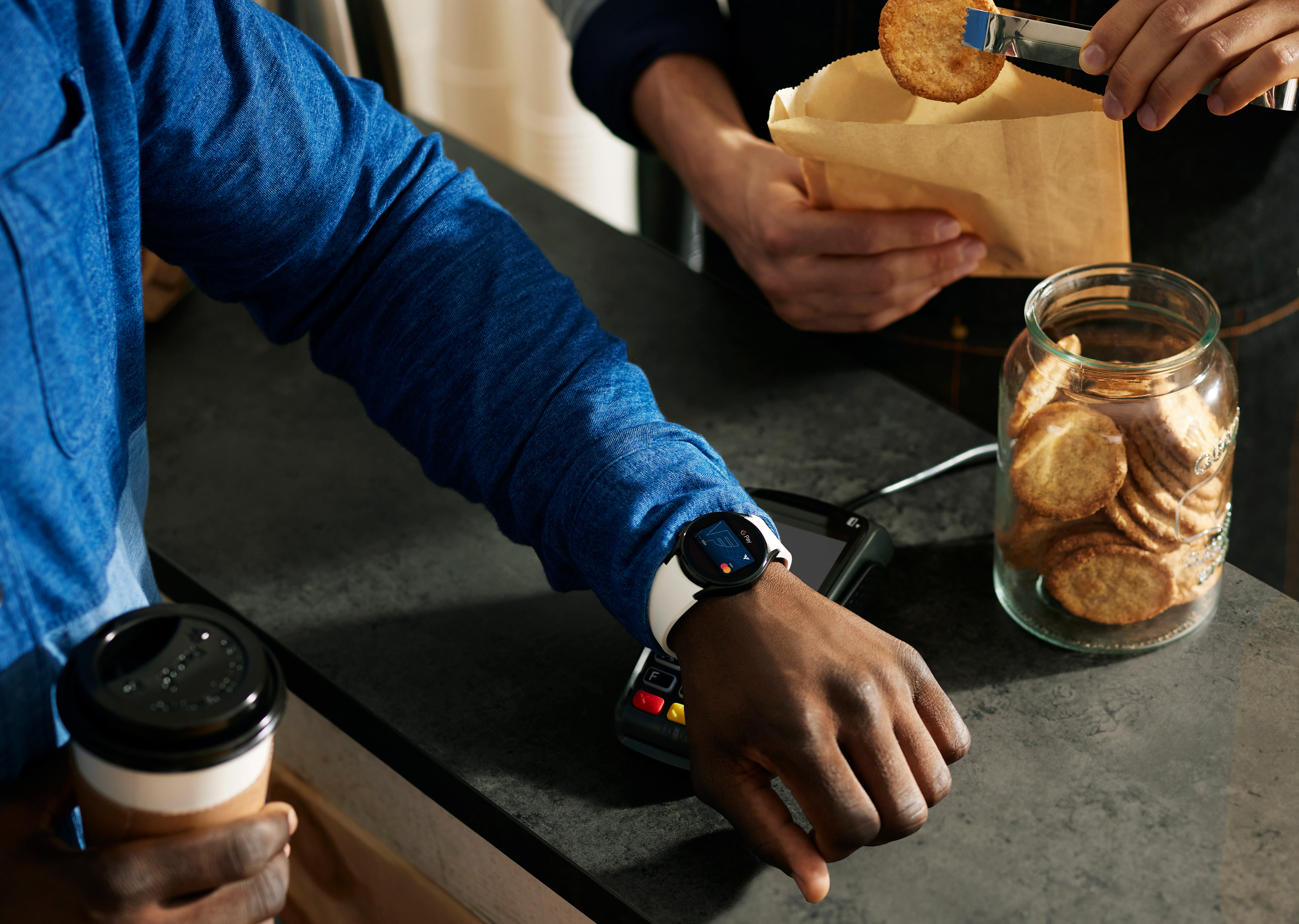 Ein Mann zahlt mit seiner Smartwatch an einem Terminal. Zu sehen ist nur sein Arm.