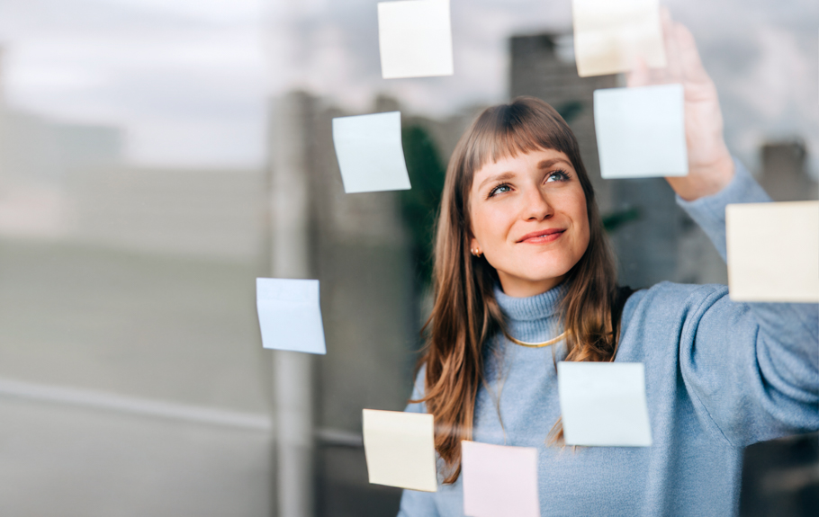 Eine junge Frau klebt Post-its auf ein Fenster.