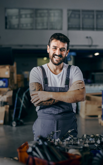 Ein Unternehmer steht in seiner Werkstatt. Man sieht viele Maschinen im Hintergrund.