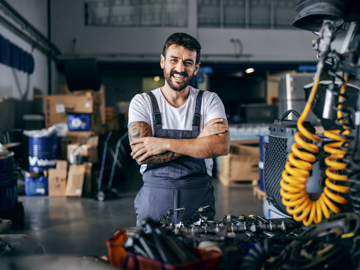 Ein Unternehmer steht in seiner Werkstatt. Man sieht viele Maschinen im Hintergrund.