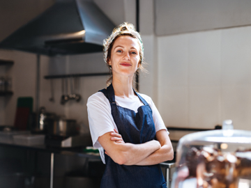 Zwei junge Unternehmer stehen in Ihrer Werkstatt vor der Werkbank und blicken auf ein Werkstück aus Holz.